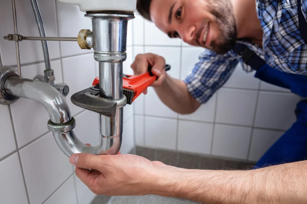 Plombier reprenant le raccordement d'une canalisation dans un immeuble parisien